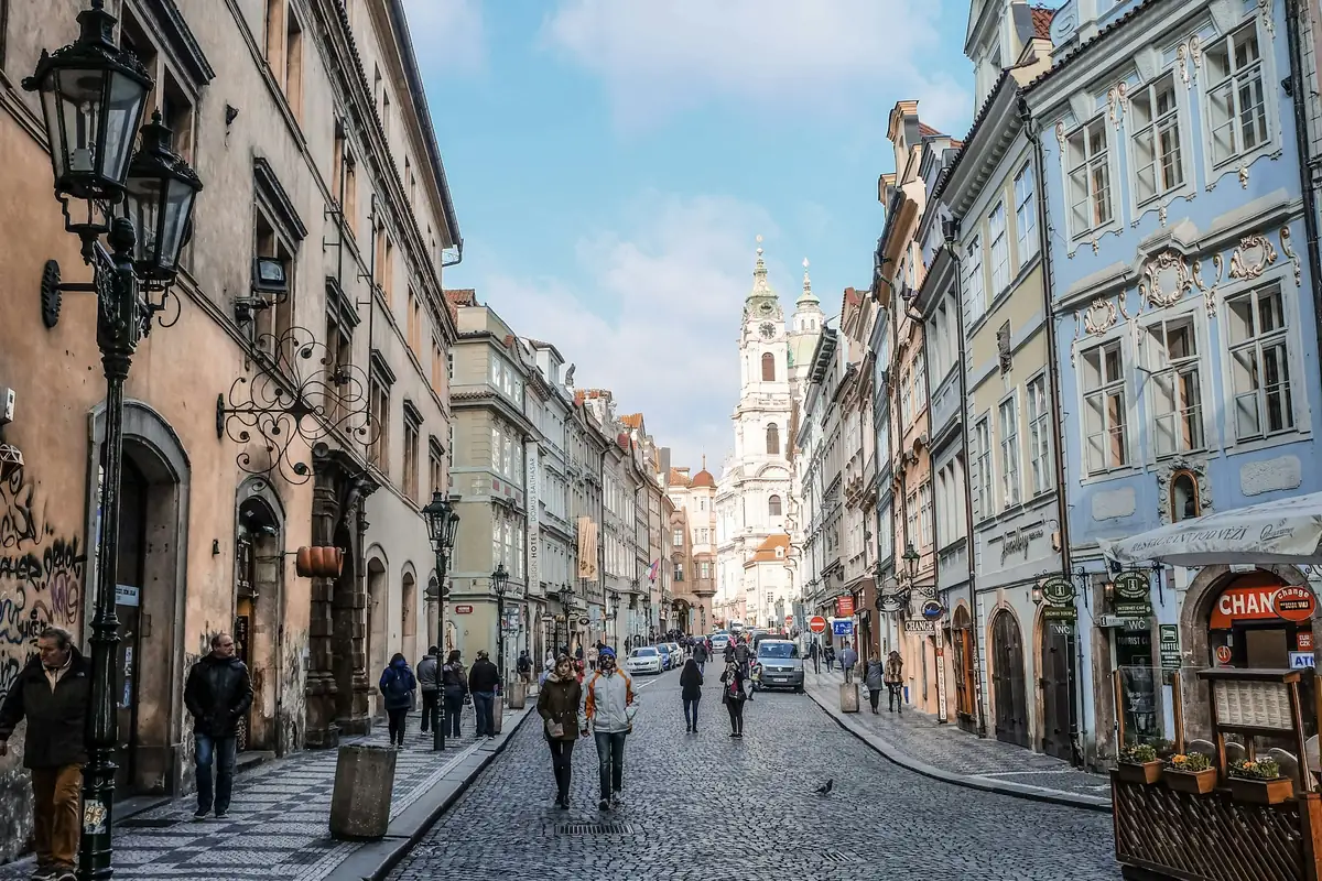 Original: A cobbled old-town street with a church tower in the distance
